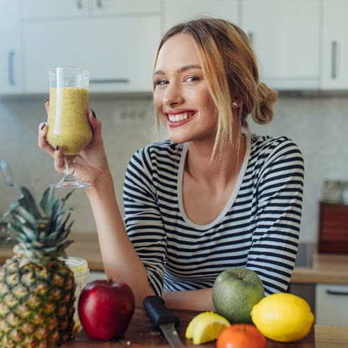 A woman smiling holding a smoothie