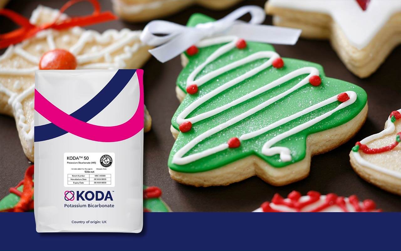 Bag of KODA™ potassium bicarbonate in foreground with holiday themed sugar cookies in background.